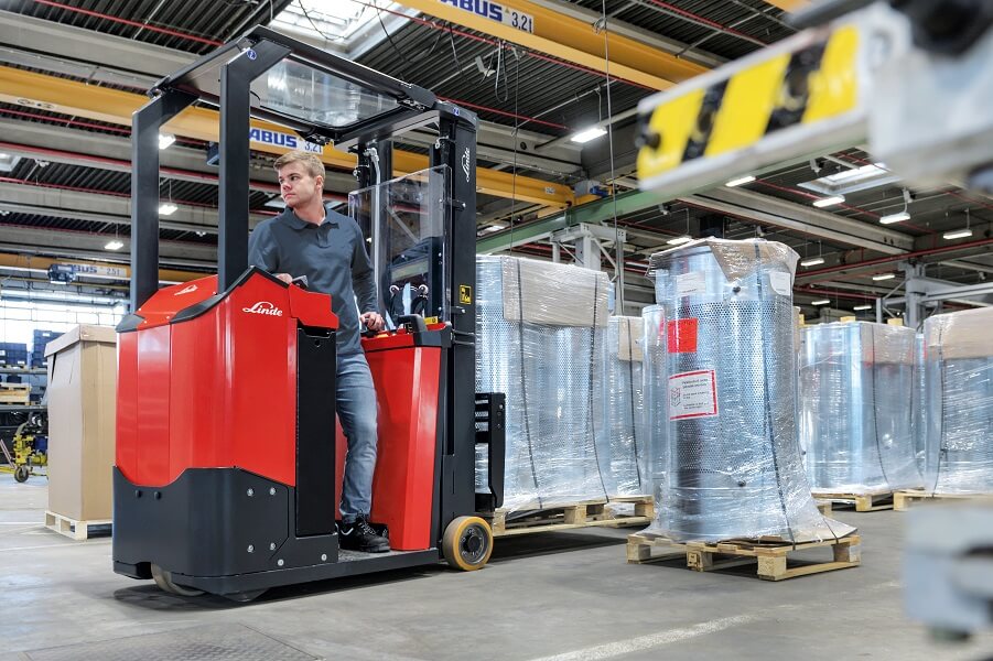 Medewerker Linde op E10 in magazijn rijdt achteruit - Compactste en wendbaarste heftruck uit gamma