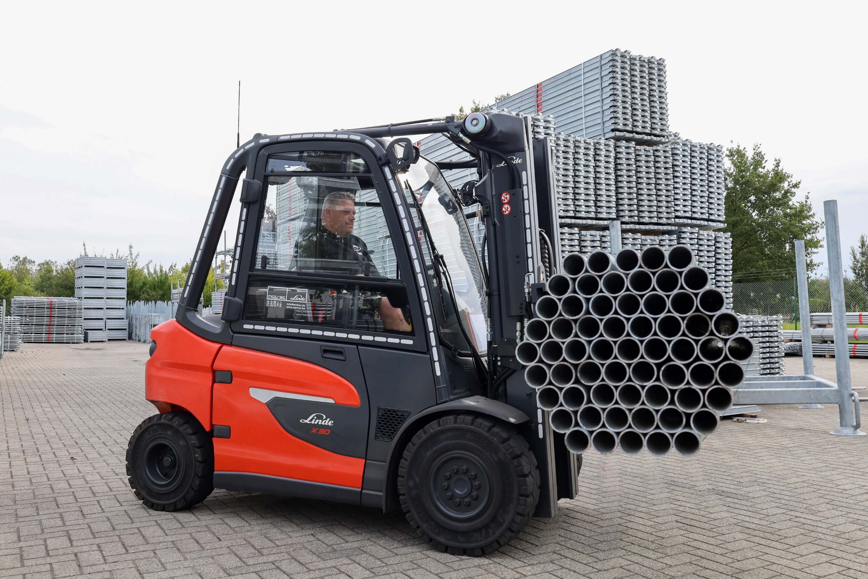Linde X30 elektrische heftruck verplaatst lange aluminium buizen op buitenterrein