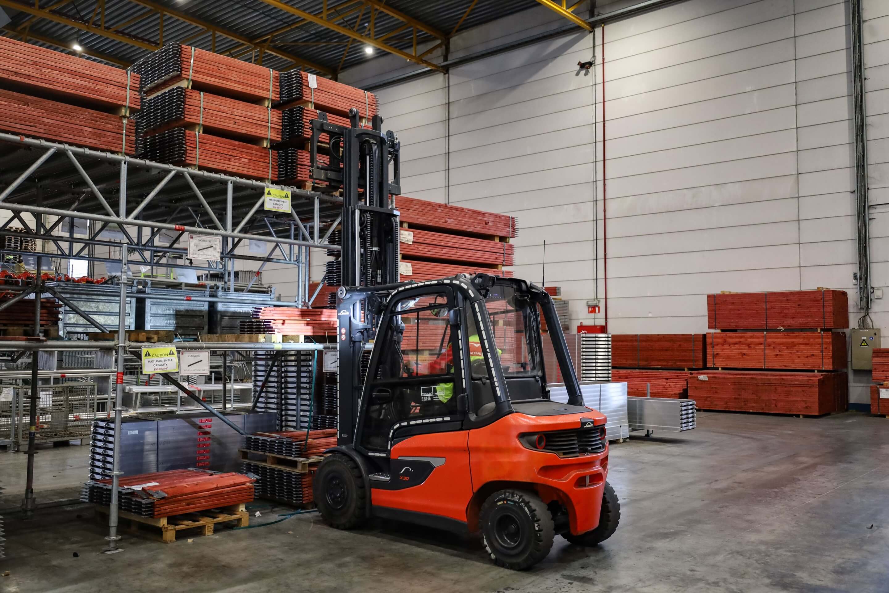 Linde X30 elektrische heftruck pikt bouwmaterialen op in magazijn linkerzijde