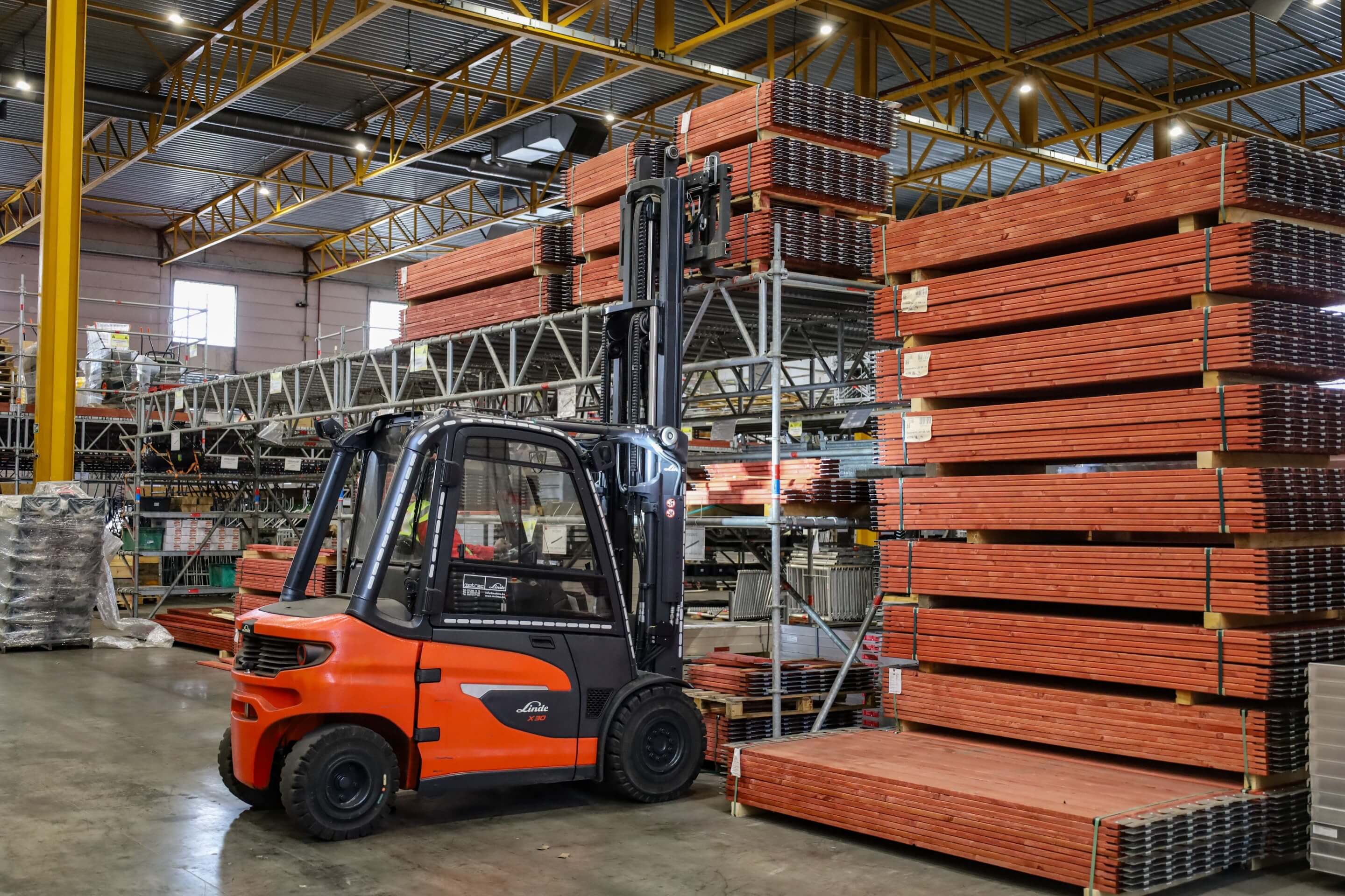 Linde X30 elektrische heftruck pikt bouwmaterialen op in magazijn rechterzijde